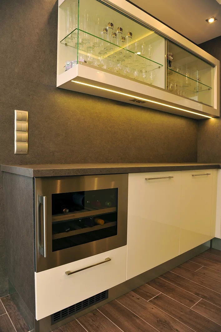 Modern beépített konyha, teljes dekoritos hátlappal, a felső szekrény helyén világított vitrinnel